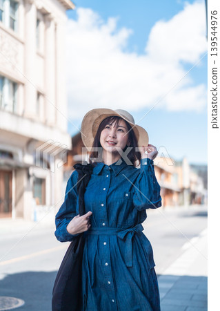 A woman in a straw hat is sightseeing in Koedo Kawagoe, looking at a map on her smartphone. She is walking around town and traveling. A woman in a straw hat is sightseeing in Koedo Kawagoe, looking at a map on her smartphone. She is walking around town and traveling. 139544976
