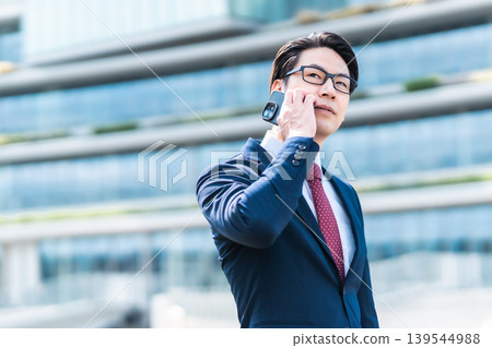 Businessmen using their smartphones to answer phone calls in the office district. Businessmen using their smartphones to answer phone calls in the office district. 139544988