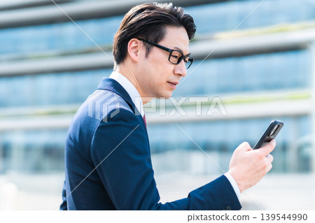 商務人士在辦公區使用智慧型手機接聽電話。 商務人士在辦公區使用智慧型手機接聽電話。 139544990