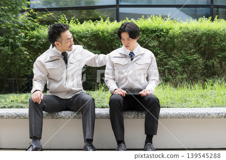 A portrait of workers conversing during a break; workplace communication, interpersonal relationships, and a supervisor encouraging a subordinate. A portrait of workers conversing during a break; workplace communication, interpersonal relationships, and a supervisor encouraging a subordinate. 139545288