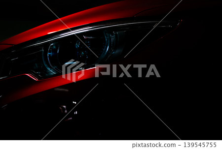 Closeup headlight of shiny red luxury SUV compact car. Elegant electric car technology and business concept. Hybrid auto and automotive concept. Car parked in showroom or motor show. Car dealership. Closeup headlight of shiny red luxury SUV compact car. Elegant electric car technology and business concept. Hybrid auto and automotive concept. Car parked in showroom or motor show. Car dealership. 139545755