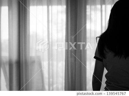 Rear view of sad adult Asian woman sitting on bed in bedroom, stressed and depressed mood. Loneliness anxiety and postpartum depression, emotional struggle in home with mental health awareness. Rear view of sad adult Asian woman sitting on bed in bedroom, stressed and depressed mood. Loneliness anxiety and postpartum depression, emotional struggle in home with mental health awareness. 139545767