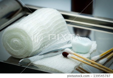 Medical professional preparing wound care dressing set with cotton ball soaked in alcohol and povidone iodine swab on stainless steel plate in clinical for hygiene treatment and infection prevention. Medical professional preparing wound care dressing set with cotton ball soaked in alcohol and povidone iodine swab on stainless steel plate in clinical for hygiene treatment and infection prevention. 139545787