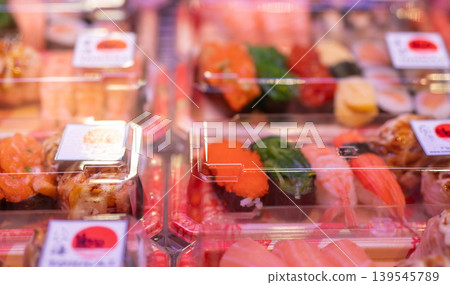 Sushi set in plastic box displayed on supermarket shelf representing Japanese takeaway food ready to eat in convenient disposable container for busy urban lifestyle and healthy meal choice. Sushi set in plastic box displayed on supermarket shelf representing Japanese takeaway food ready to eat in convenient disposable container for busy urban lifestyle and healthy meal choice. 139545789