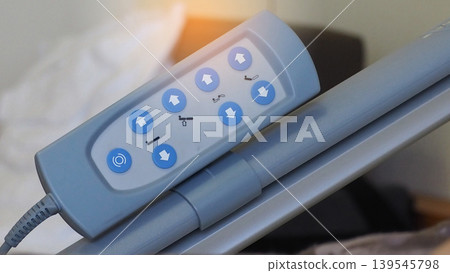 Closeup remote control panel of electric adjustable bed use for adjust patient's bed for comfortable. Adjustable hospital bed. Remote with 8 blue button. Electric hospital bed for disabled person. Closeup remote control panel of electric adjustable bed use for adjust patient's bed for comfortable. Adjustable hospital bed. Remote with 8 blue button. Electric hospital bed for disabled person. 139545798