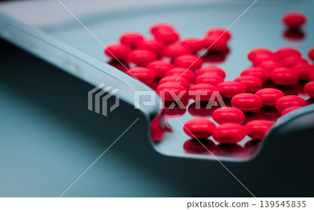 Red round sugar coated tablet pills arranged on stainless steel drug tray in pharmacy. Pharmaceutical industry concept. Medication preparation, dosage control and hygiene standard in healthcare. Red round sugar coated tablet pills arranged on stainless steel drug tray in pharmacy. Pharmaceutical industry concept. Medication preparation, dosage control and hygiene standard in healthcare. 139545835