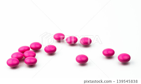 Pile of pink round sugar coated tablets pills isolated on white background with copy space. Colorful pills for treatment anti anxiety, antidepressant and migraine headache prophylaxis. Pile of pink round sugar coated tablets pills isolated on white background with copy space. Colorful pills for treatment anti anxiety, antidepressant and migraine headache prophylaxis. 139545838