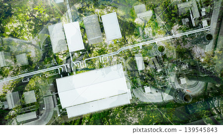 Aerial view factory roof amidst lush green tree forest. Sustainable practices for carbon reduction of factories. Sustainability in manufacturing. Carbon offsets and eco-friendly industrial practices. 139545843