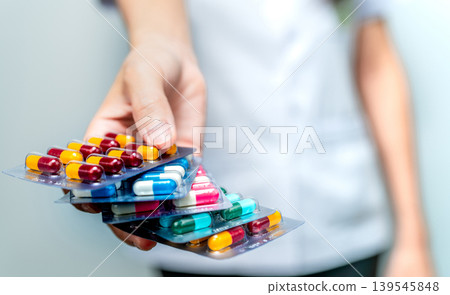 Pharmacist or doctor hand holding pack of antibiotic capsule pills and giving patient or people. Antibiotic drug overuse. Antimicrobial drug resistance. Community pharmacist. Drugstore background. Pharmacist or doctor hand holding pack of antibiotic capsule pills and giving patient or people. Antibiotic drug overuse. Antimicrobial drug resistance. Community pharmacist. Drugstore background. 139545848