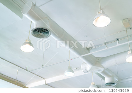Air duct, air conditioner pipe and fire sprinkler system on white ceiling wall. Air flow and ventilation system. Building interior. Ceiling lamp light with opened light. Interior architecture concept. Air duct, air conditioner pipe and fire sprinkler system on white ceiling wall. Air flow and ventilation system. Building interior. Ceiling lamp light with opened light. Interior architecture concept. 139545929
