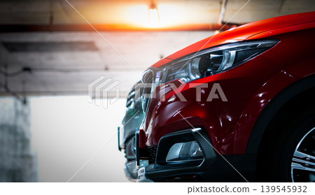 Selective focus on red shiny SUV sport car parked at shopping mall indoor parking lot. Headlamp lights with elegant and luxury design. Automotive industry and hybrid car concept. Underground parking. Selective focus on red shiny SUV sport car parked at shopping mall indoor parking lot. Headlamp lights with elegant and luxury design. Automotive industry and hybrid car concept. Underground parking. 139545932
