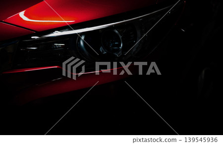 Closeup headlight of shiny red luxury SUV compact car. Elegant electric car technology and business concept. Hybrid auto and automotive concept. Car parked in showroom or motor show. Car dealership. 139545936