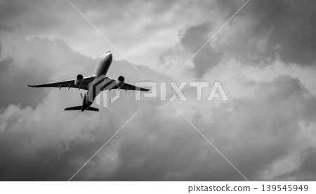 Commercial airplane flying in grey cloudy sky. Failed vacation and travel disruption, emotional concept of despair, hopelessness and uncertainty in aviation journey under stormy weather conditions. Commercial airplane flying in grey cloudy sky. Failed vacation and travel disruption, emotional concept of despair, hopelessness and uncertainty in aviation journey under stormy weather conditions. 139545949