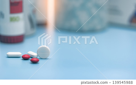 Round white tablets and blurred red and white tablets pills. Pills on blurred pills plastic bottle. Healthcare and pharmaceutical industry. Pharmacy or polypharmacy concept. Prescription drugs. Round white tablets and blurred red and white tablets pills. Pills on blurred pills plastic bottle. Healthcare and pharmaceutical industry. Pharmacy or polypharmacy concept. Prescription drugs. 139545988