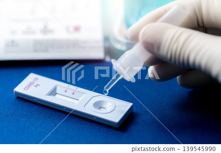 Hand holding sample tube and drops in the test device of covid 19 antigen self test. Antigen test kit for detection of coronavirus infection. Rapid antigen test. Coronavirus diagnosis. Medical device. Hand holding sample tube and drops in the test device of covid 19 antigen self test. Antigen test kit for detection of coronavirus infection. Rapid antigen test. Coronavirus diagnosis. Medical device. 139545990