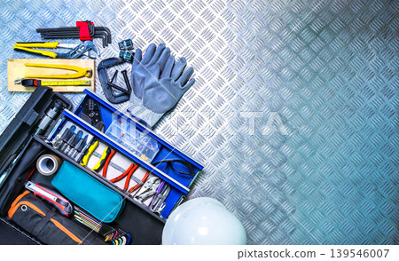 Top view toolbox and safety helmet on checkered plate background in workshop, service tools set for construction electrical and plumbing repair, concept of technician equipment, maintenance work. Top view toolbox and safety helmet on checkered plate background in workshop, service tools set for construction electrical and plumbing repair, concept of technician equipment, maintenance work. 139546007