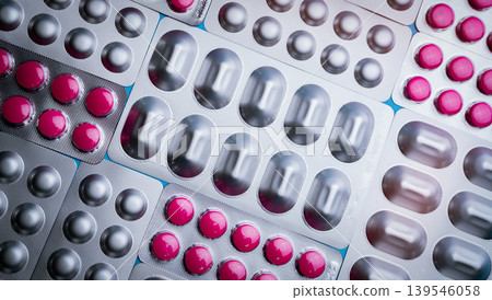 Pink tablets in blister pack and silver aluminium foil pack for capsule and tablets pills in pharmaceutical industry. Pharmaceutical package manufacturing. Top view of round tablets pills. Pharmacy. 139546058