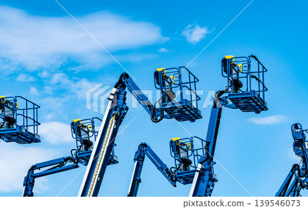 Articulated boom lift. Aerial platform lift. Telescopic boom lift against blue sky. Mobile construction crane for rent and sale. Maintenance and repair hydraulic boom lift service. Crane dealership. Articulated boom lift. Aerial platform lift. Telescopic boom lift against blue sky. Mobile construction crane for rent and sale. Maintenance and repair hydraulic boom lift service. Crane dealership. 139546073