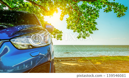 Blue sport SUV car parked by the tropical sea under umbrella tree. Summer vacation at the beach. Summer travel by car. Road trip. Automotive industry. Hybrid and electric car concept. Summer vibes. Blue sport SUV car parked by the tropical sea under umbrella tree. Summer vacation at the beach. Summer travel by car. Road trip. Automotive industry. Hybrid and electric car concept. Summer vibes. 139546081