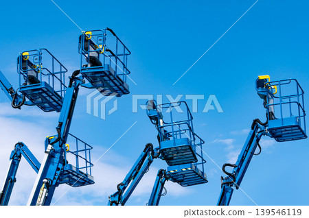 Articulated boom lift. Aerial platform lift. Telescopic boom lift against blue sky. Mobile construction crane for rent and sale. Maintenance and repair hydraulic boom lift service. Crane dealership. Articulated boom lift. Aerial platform lift. Telescopic boom lift against blue sky. Mobile construction crane for rent and sale. Maintenance and repair hydraulic boom lift service. Crane dealership. 139546119
