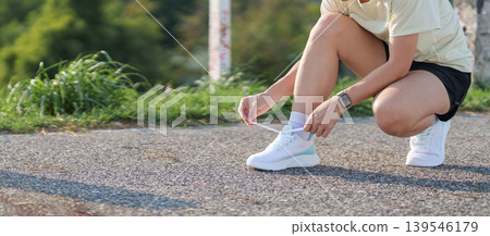 Young Asian woman tying running shoes in the park. Female runner getting ready for jogging and exercise on the road. Fitness, wellness and outdoor sport concept in morning Young Asian woman tying running shoes in the park. Female runner getting ready for jogging and exercise on the road. Fitness, wellness and outdoor sport concept in morning 139546179