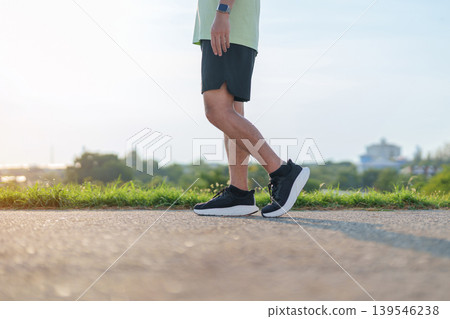 Young adult Asian man jogging and walking in the park at morning. male athlete in sport shoes running on the road with visible leg muscles. Healthy lifestyle, wellness and workout concept 139546238