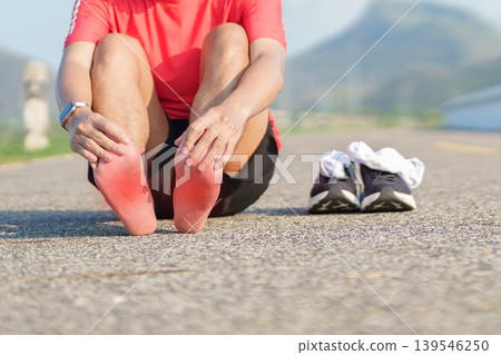 Young adult male runner suffering from acute plantar fasciitis pain during running workout. Man holding his foot due to heel inflammation and sports injury. Medical and healthcare concept Young adult male runner suffering from acute plantar fasciitis pain during running workout. Man holding his foot due to heel inflammation and sports injury. Medical and healthcare concept 139546250