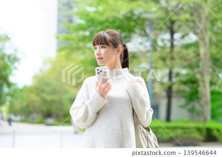 Woman holding a smartphone, outdoors Woman holding a smartphone, outdoors 139546644