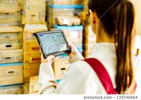 A woman operating a tablet in a warehouse. A woman operating a tablet in a warehouse. 139546664