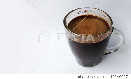 Hot black coffee in a glass cup with crema on a white background. Hot black coffee in a glass cup with crema on a white background. 139546697