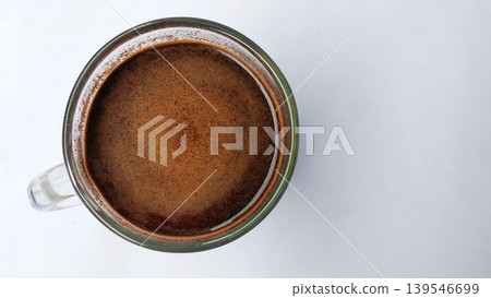 Hot black coffee in a glass cup with crema on a white background. Hot black coffee in a glass cup with crema on a white background. 139546699