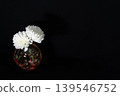 A single white chrysanthemum in a cool-toned, spherical glass vase, floating in the darkness (placed on the left). A single white chrysanthemum in a cool-toned, spherical glass vase, floating in the darkness (placed on the left). 139546752