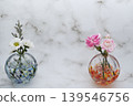 A pair of pink and white flowers in a spherical glass vase. A pair of pink and white flowers in a spherical glass vase. 139546756