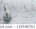A single flower in a cool-toned spherical glass vase, featuring a white chrysanthemum and a blue fantasia (placed on the left). A single flower in a cool-toned spherical glass vase, featuring a white chrysanthemum and a blue fantasia (placed on the left). 139546761