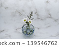 A single flower in a cool-toned spherical glass vase, featuring a white chrysanthemum and a blue fantasia (center placement). A single flower in a cool-toned spherical glass vase, featuring a white chrysanthemum and a blue fantasia (center placement). 139546762