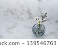 A single flower in a cool-toned spherical glass vase, featuring a white chrysanthemum and a blue fantasia (arranged on the right). A single flower in a cool-toned spherical glass vase, featuring a white chrysanthemum and a blue fantasia (arranged on the right). 139546763