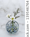 A single flower in a cool-toned spherical glass vase, featuring a white chrysanthemum and a blue fantasia (vertical composition). A single flower in a cool-toned spherical glass vase, featuring a white chrysanthemum and a blue fantasia (vertical composition). 139546764