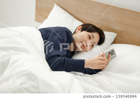A woman watching a smartphone in bed A woman watching a smartphone in bed 139546994