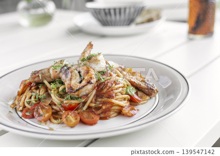 shrimp and tomato diavolo spicy spaghetti on white table at outdoor restaurant in italy 139547142