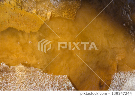 Turbid stream's yellowish water churns with rising silt, framed by sharp, fractured ice remnants. A raw, natural vista Turbid stream's yellowish water churns with rising silt, framed by sharp, fractured ice remnants. A raw, natural vista 139547244