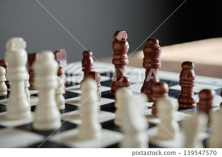 Brown chess pieces facing white pieces on chessboard 139547570