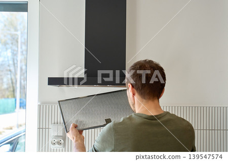 Person removing kitchen hood filter in modern home kitchen Person removing kitchen hood filter in modern home kitchen 139547574