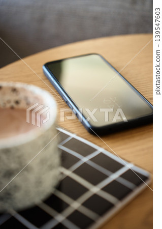 Smartphone lying on table beside coffee cup 139547603