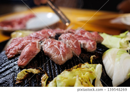 Raw lamb being grilled in a Genghis Khan hot pot Raw lamb being grilled in a Genghis Khan hot pot 139548269
