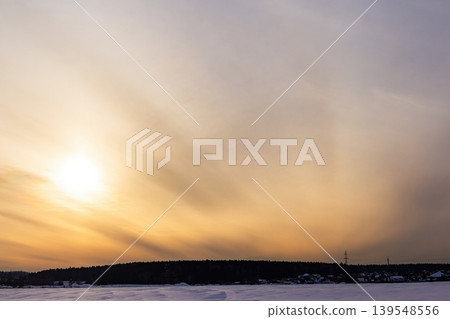 Vast snowy field under a breathtaking winter sunset. Golden sunbeams pierce the vibrant sky creating a serene picturesque horizon. Pure nature's charm Vast snowy field under a breathtaking winter sunset. Golden sunbeams pierce the vibrant sky creating a serene picturesque horizon. Pure nature's charm 139548556