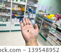a medicine capsule on a palm with blurry pharmacy shelves background. Concept of healthcare, pharmaceutical treatment, medical prescription, and drug dosage in drug store setting 139548952