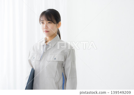 A woman in work clothes checking something A woman in work clothes checking something 139549209
