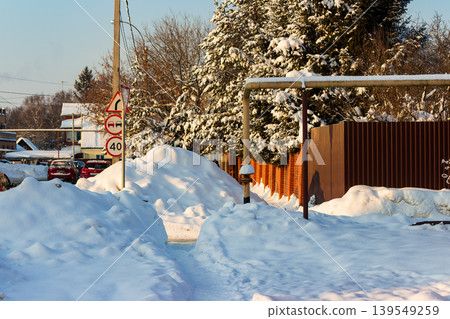 Deep winter scene with towering snowdrifts lining a narrow path, bright sunlight illuminating the fresh powder and evergreen trees Deep winter scene with towering snowdrifts lining a narrow path, bright sunlight illuminating the fresh powder and evergreen trees 139549259