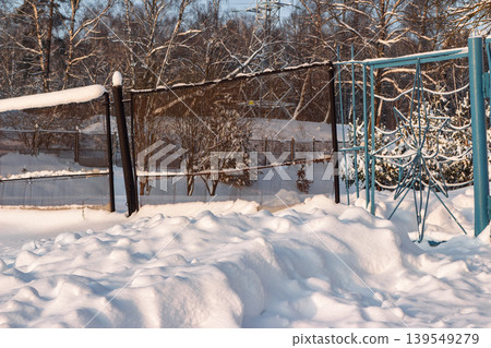 Deep snowdrifts pile high beside a dark fence line on a crisp winter afternoon as low sunlight bathes the scene in a warm glow Deep snowdrifts pile high beside a dark fence line on a crisp winter afternoon as low sunlight bathes the scene in a warm glow 139549279