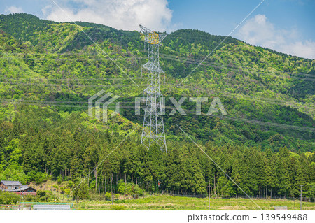 在滋賀縣長濱市西淺井町,一座輸電塔矗立在綠意盎然的山巒之中。 在滋賀縣長濱市西淺井町,一座輸電塔矗立在綠意盎然的山巒之中。 139549488